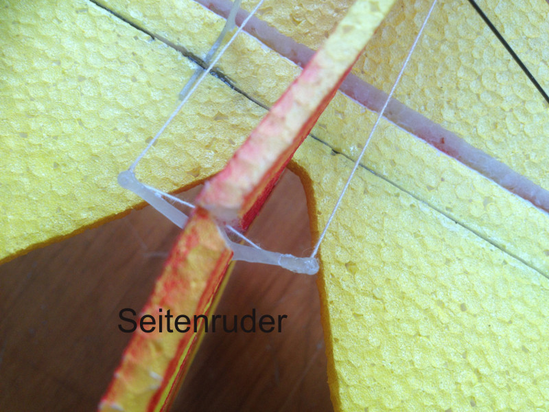 Ruder einschlitzen und Ruderarm einkleben. Die kleine Nase in der Mitte des Ruderarms soll auf die angeschliffene Spitze des angeschliffenen Scharnierspaltes zeigen.